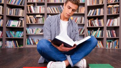 doing his research in library concentrated young man reading book while sitting against bookshelf free photo optimized scaled